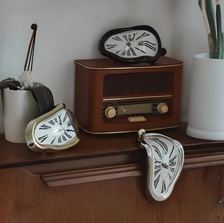 Silver surrealist melting clock resting on the edge of a metal bookshelf next to books